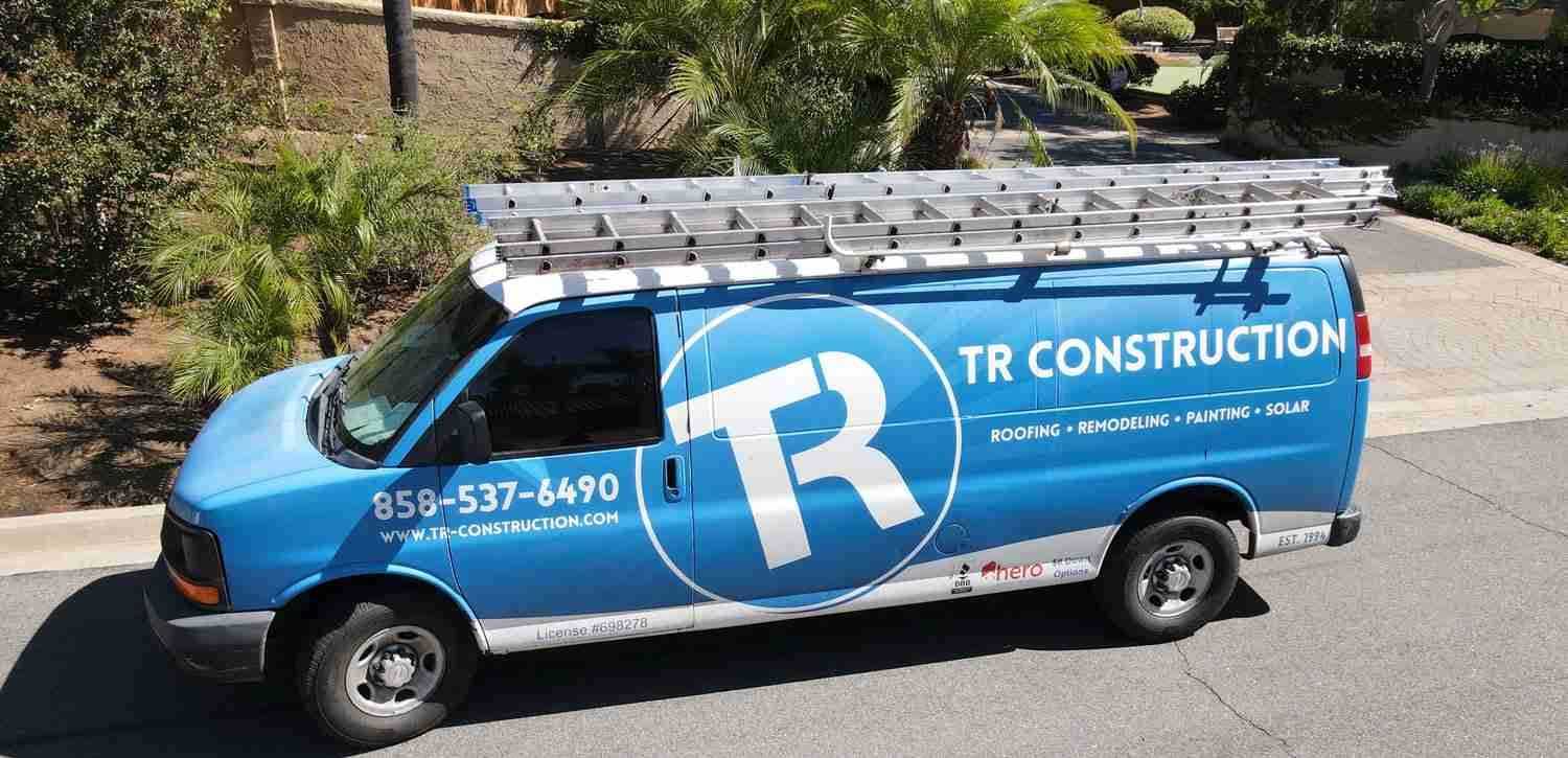 TR Construction work van with ladders on the roof rack, showing the company phone number, license number and services