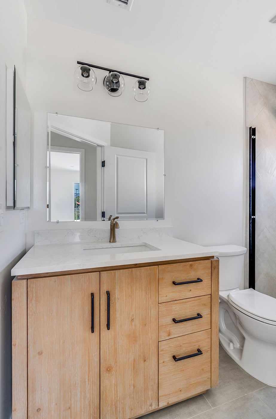 ADU bathroom vanity with wood cabinets and a wall mirror