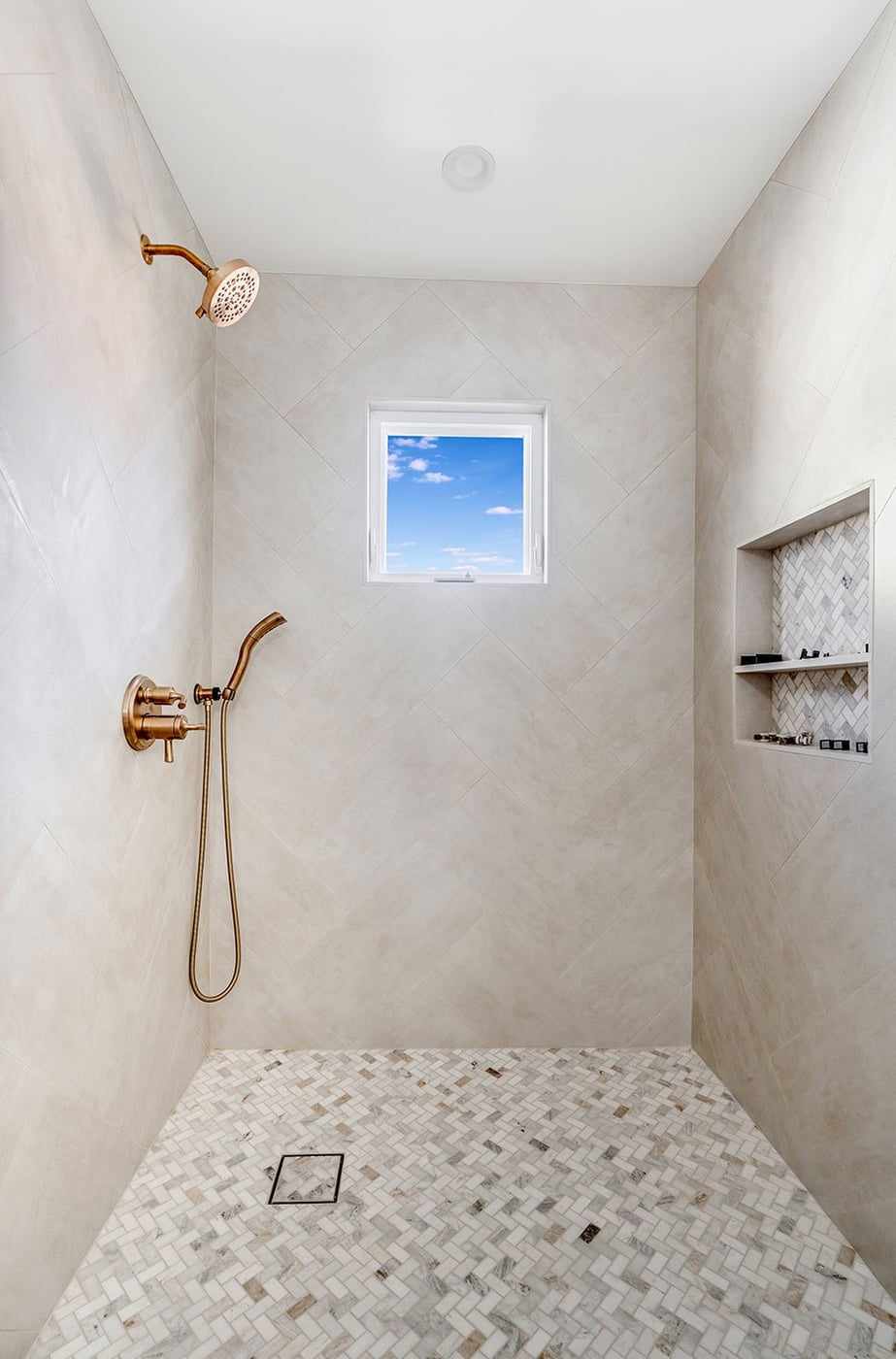 Walk-in tile shower with a niche and a small window