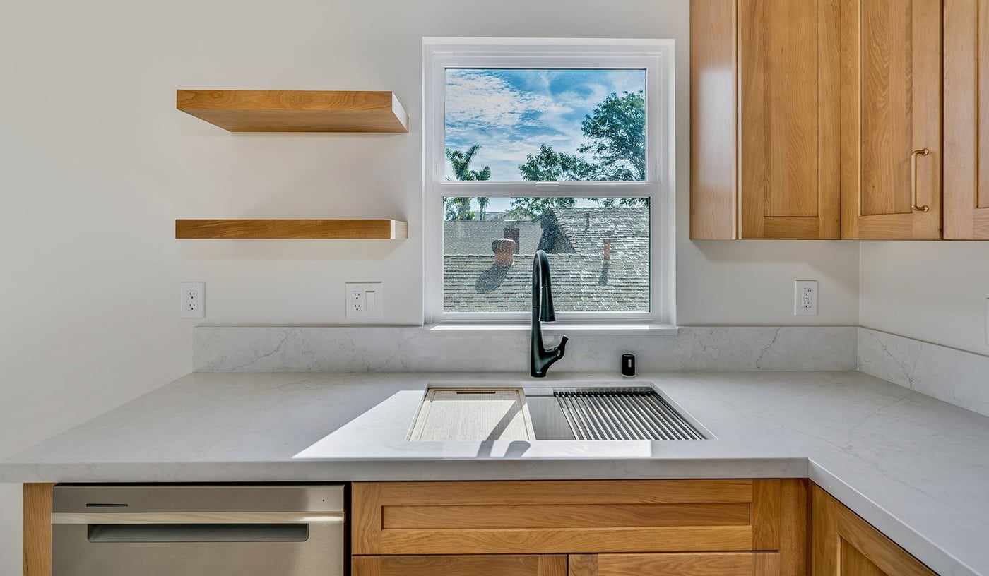 ADU kitchen sink under a window, with floating shelves