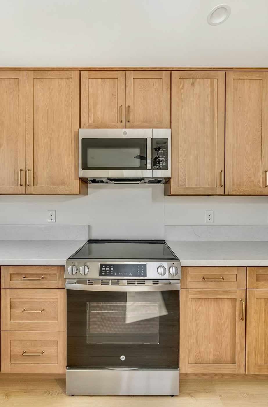 ADU range and microwave between wood cabinets
