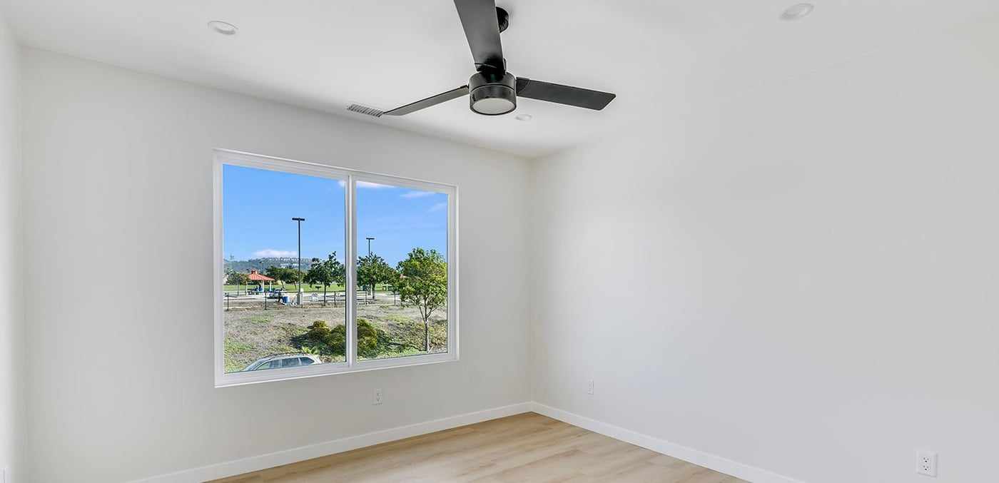 ADU bedroom, empty, with a window and a ceiling fan