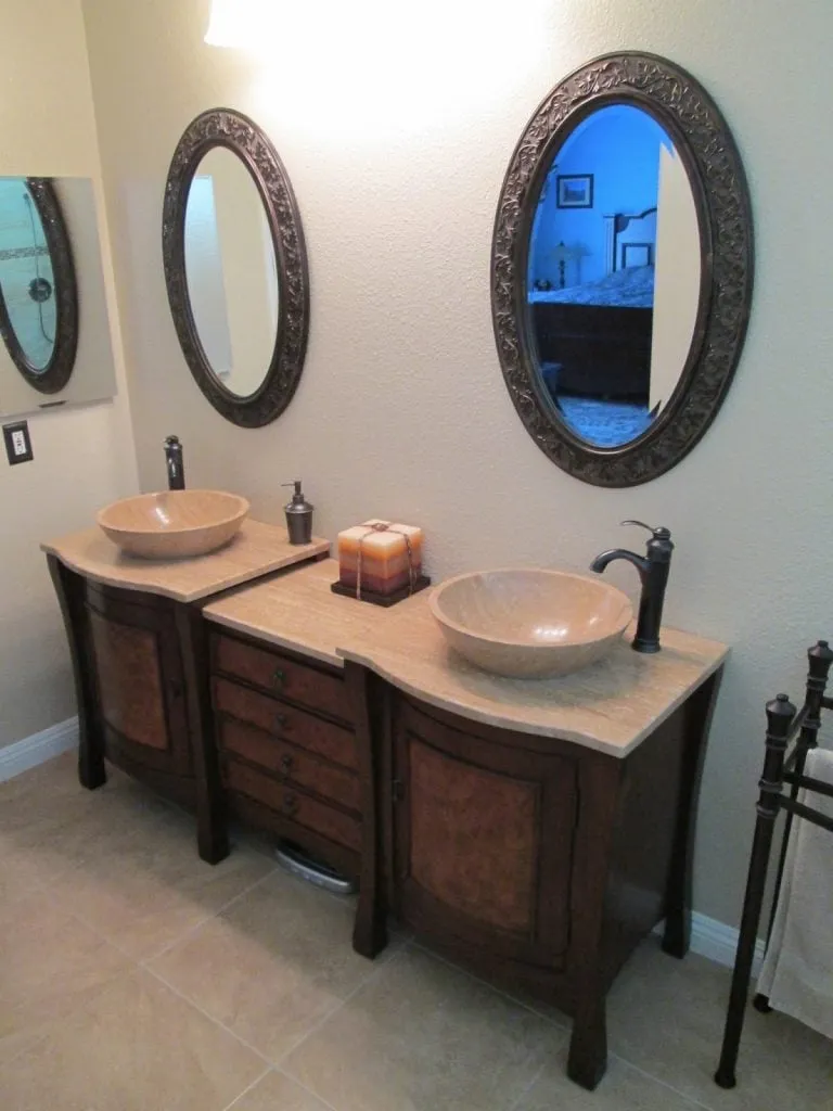 Bathroom with two vessel sinks on wood vanities and oval mirrors