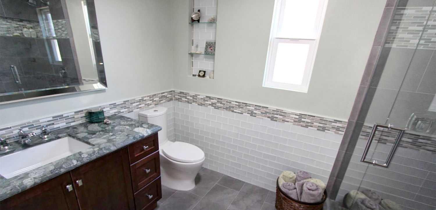 Small bathroom remodel with a glass shower enclosure, subway tile wainscoting with a glass mosaic border, a tiled wall niche and a new window