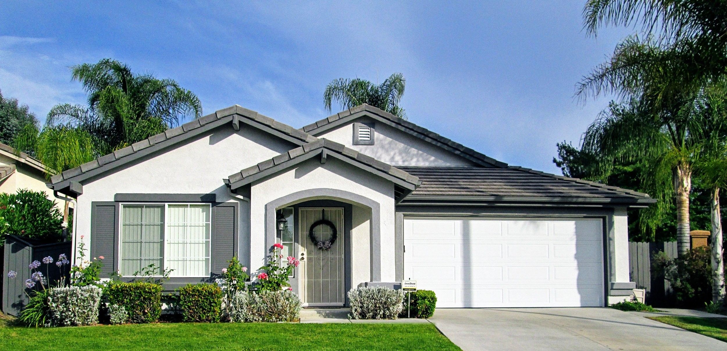 Freshly painted single-story home with gray trim and a white garage door