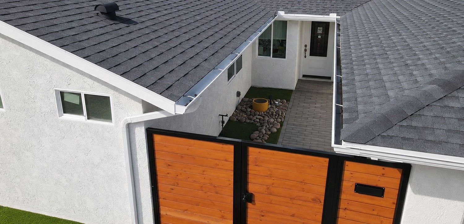 New gray shingle roof with white gutters over a home and courtyard in Mira Mesa