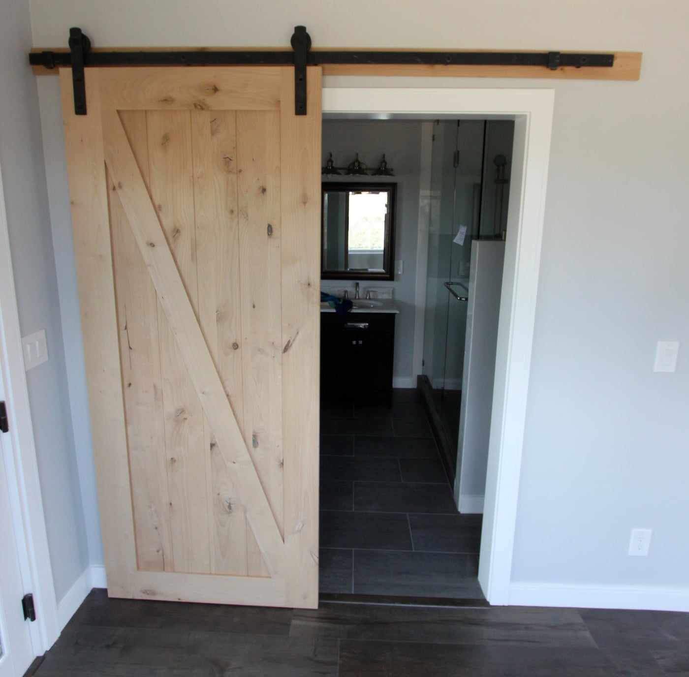 Wood barn door on a sliding rail, open to a bathroom