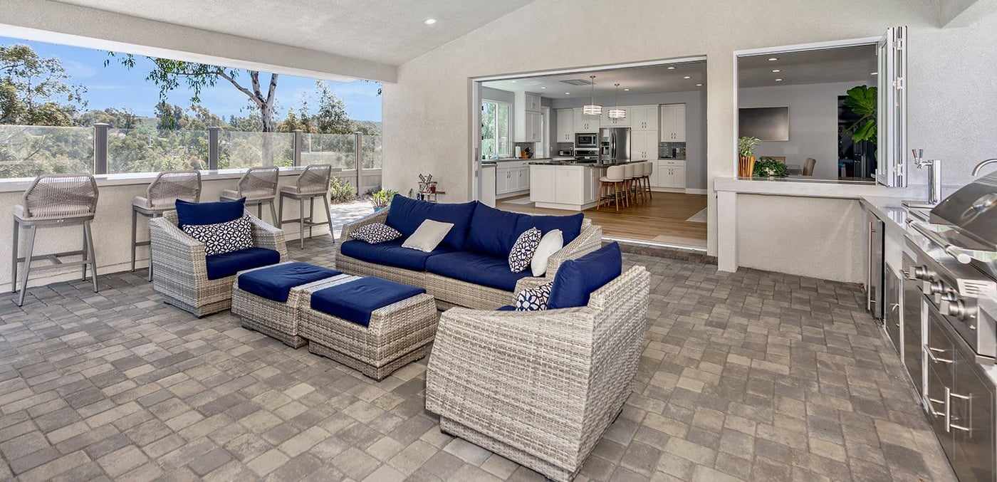 Covered patio with an outdoor kitchen at a Scripps Ranch home, looking back into the house through the open folding doors