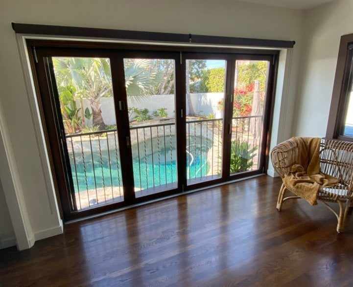 Dark-framed folding glass doors with a railing, overlooking the pool at a San Diego home