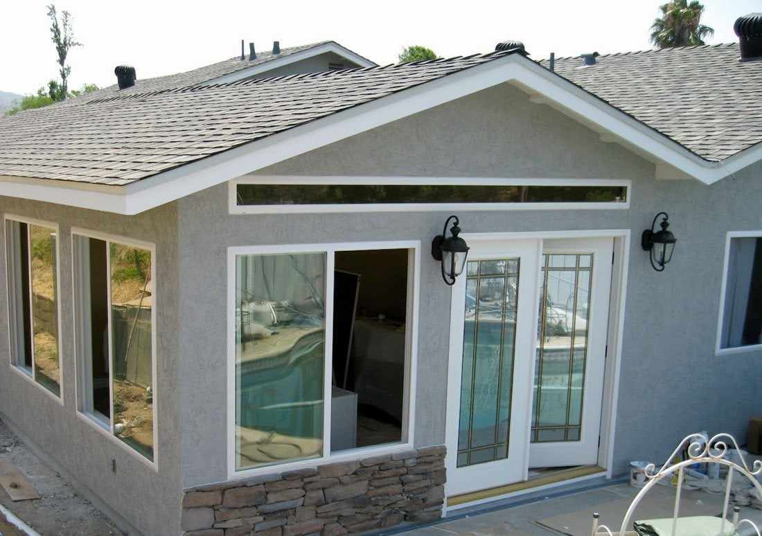 The finished room addition on a San Diego home, with stone veneer, French doors and windows facing the pool
