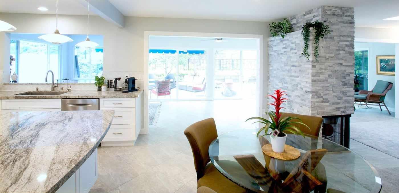 Open kitchen and dining area in a home addition, beside a stone-clad fireplace column