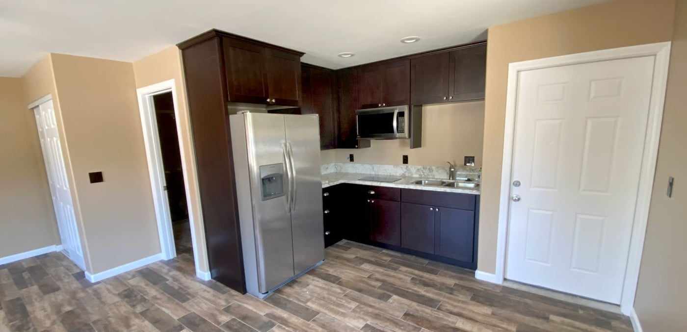 Kitchen in the garage conversion ADU, with dark cabinets and a stainless steel refrigerator