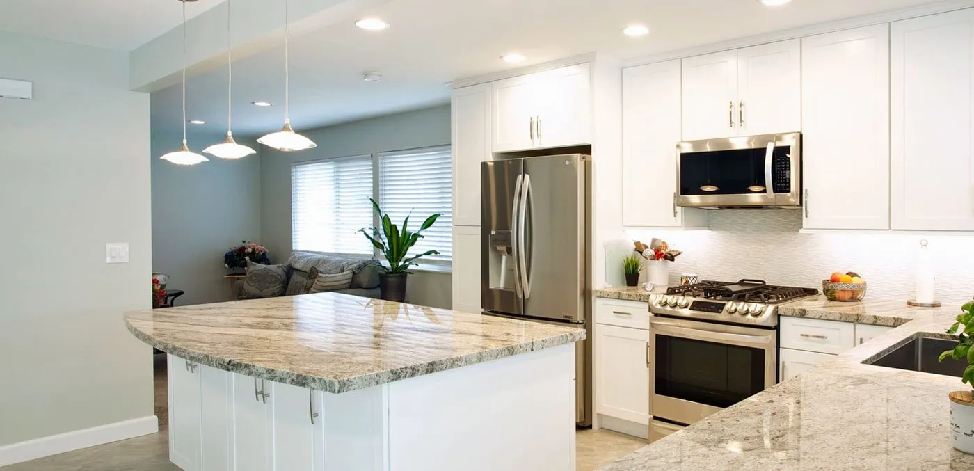 Kitchen with white cabinets, a granite island and pendant lights