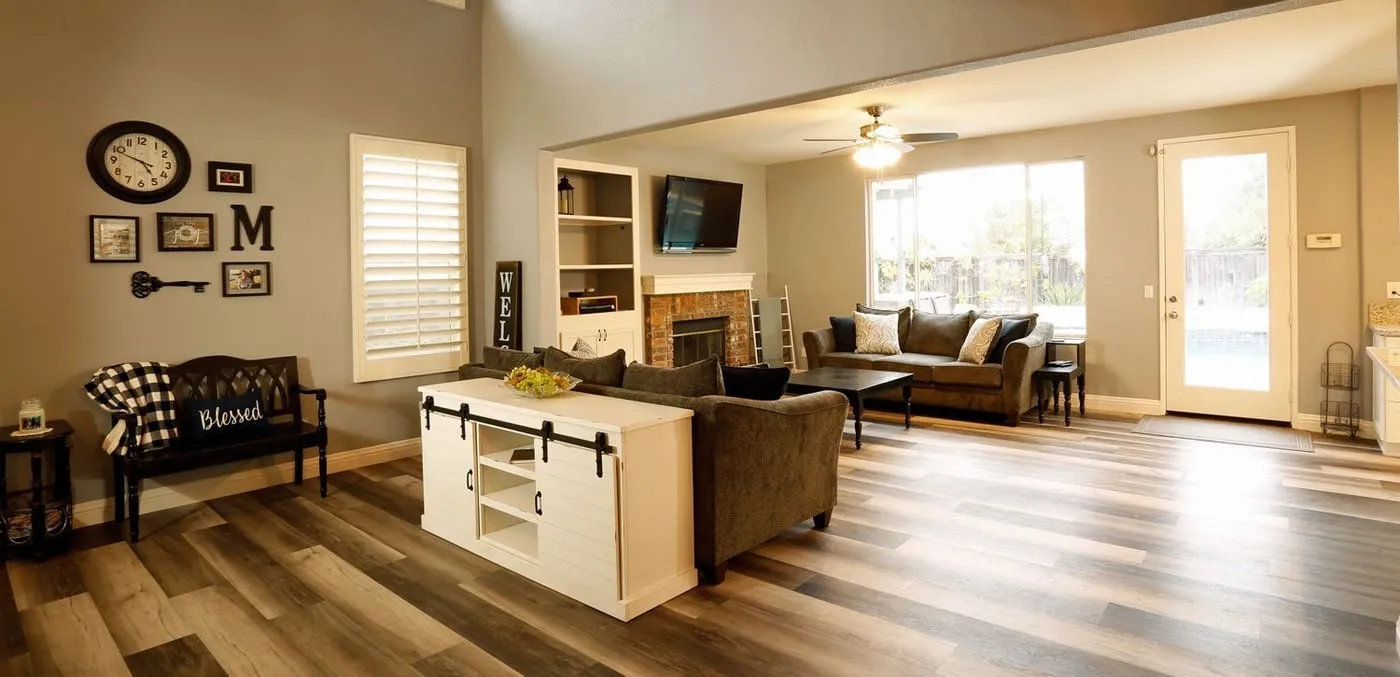 Living room with wood-look floors, a fireplace and plantation shutters