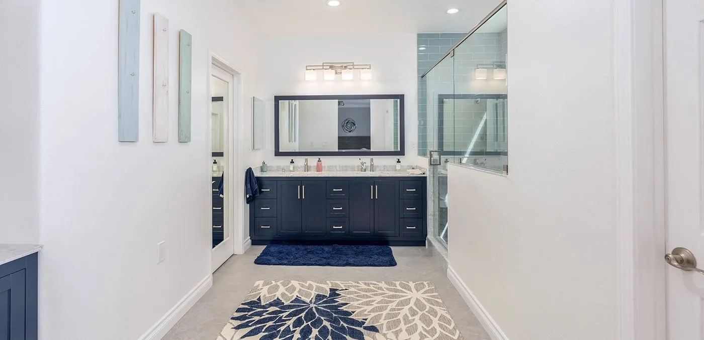 Remodeled bathroom with a navy double vanity and a glass-enclosed shower