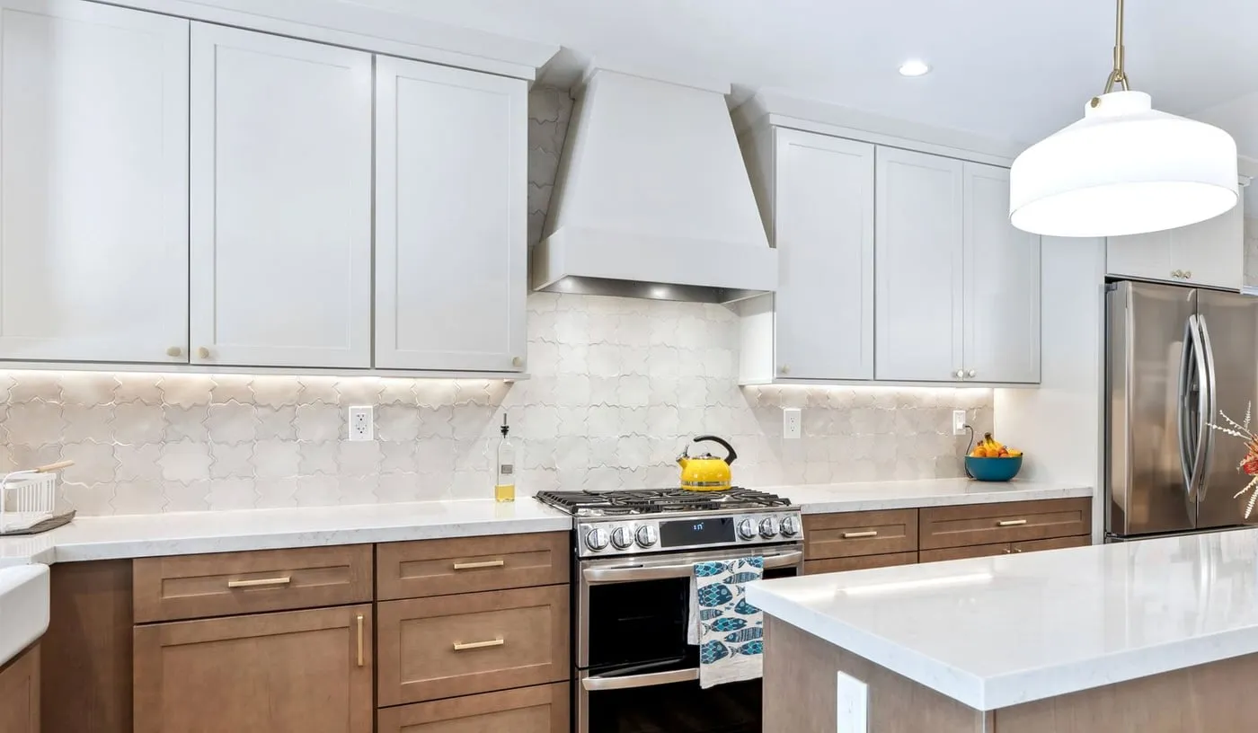 Remodeled kitchen with white upper cabinets, wood lower cabinets and a range hood