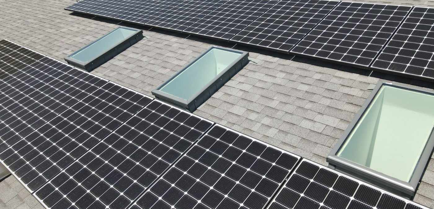 Solar panels around three skylights on the shingle roof of a Clairemont home