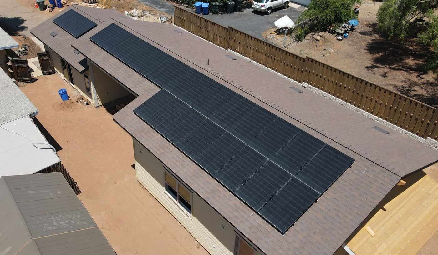 Aerial view of black solar panels along the long roof of a single-story San Diego home
