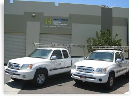 Two TR Construction pickup trucks with ladder racks parked outside the TR Construction office