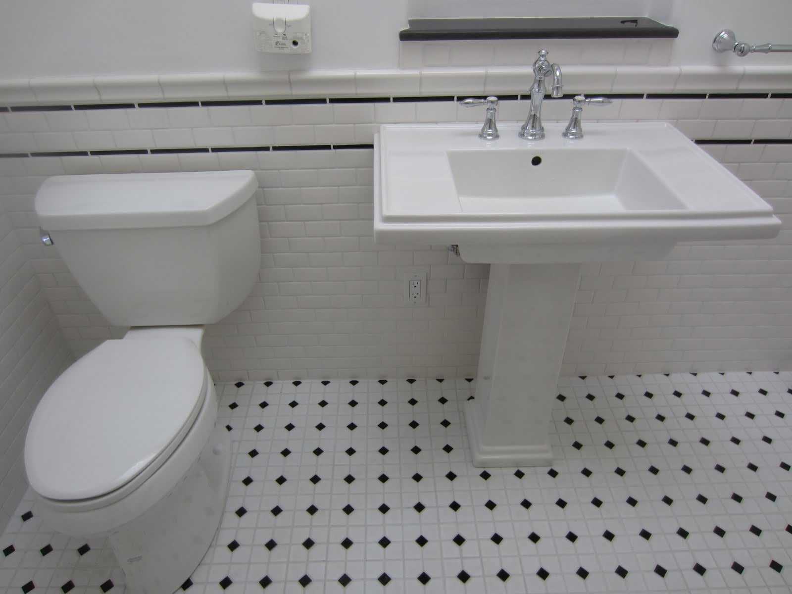 Vintage subway tile bathroom remodel: white subway tile wainscoting with black accent strips, a pedestal sink and a black and white mosaic floor
